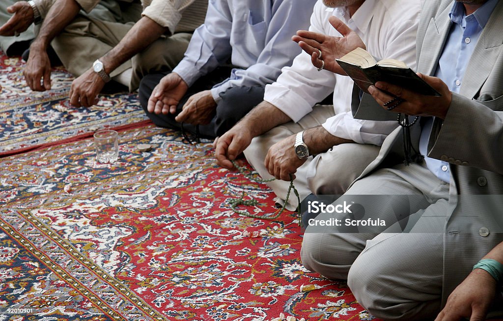 مجموعة من المصلين المسلمين يجلسون على سجادة صلاة حمراء مزخرفة في جماعة يقرؤون القرآن ويذكرون الله